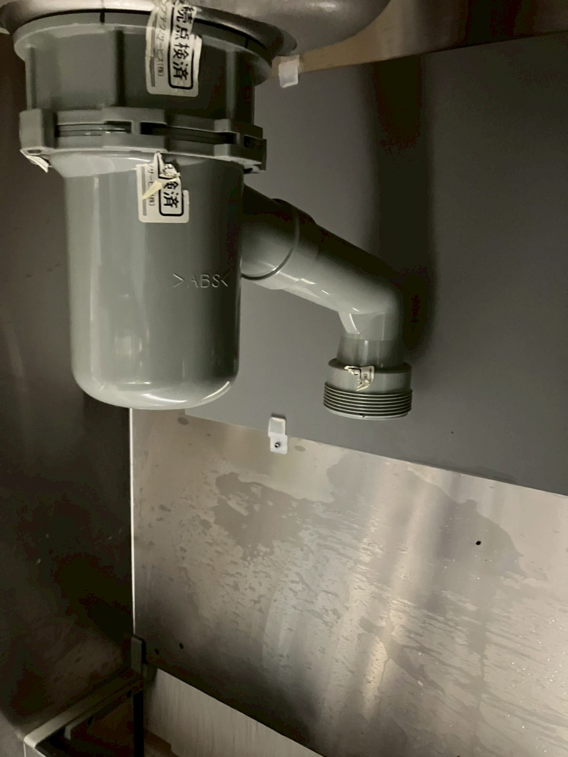 シンク下のABS製排水トラップ。清掃・確認後の状態。蛇腹ホースとの接続部も確認できる