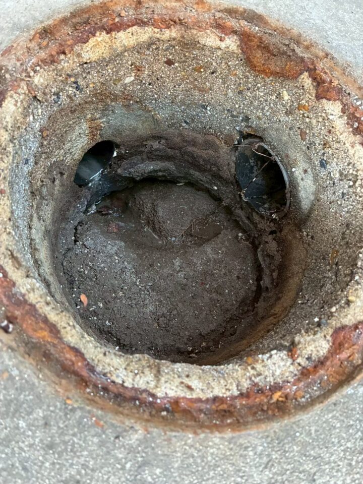 排水桝内部の施工前の状態。土砂・汚泥が堆積し、配管開口部がほぼ塞がれている