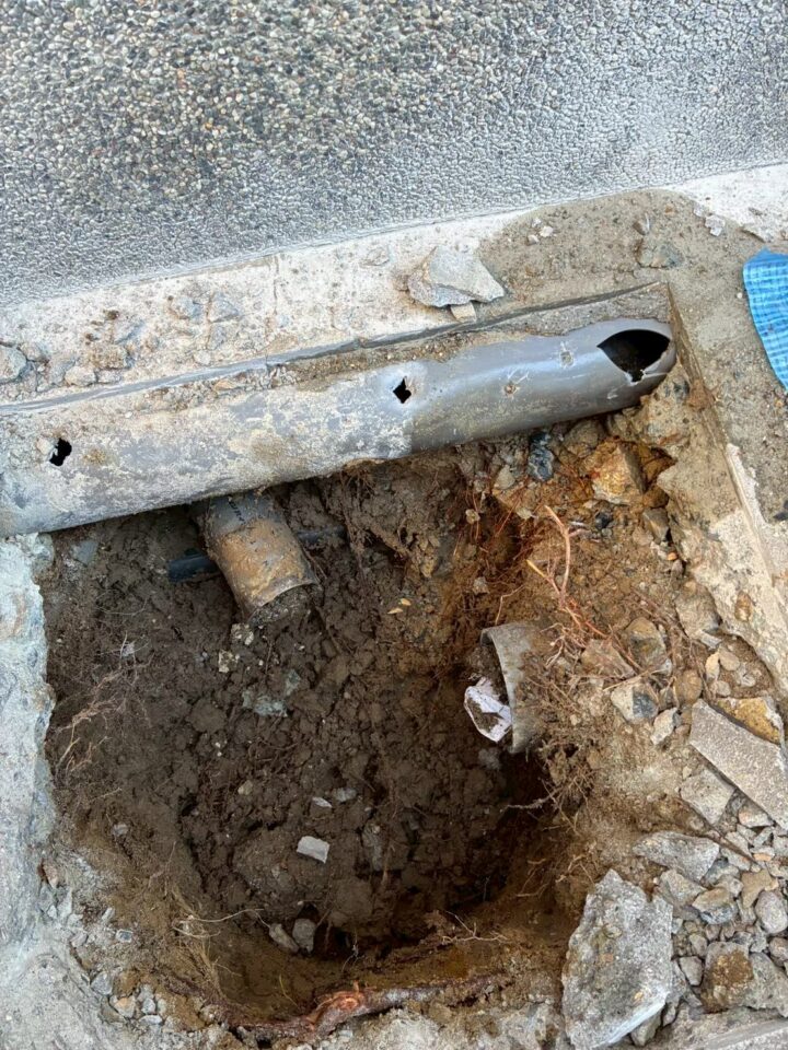 掘削後の既存配管。腐食・穴あき・変形が見られ草木の根が絡まっている