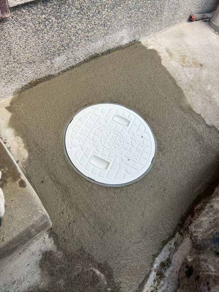 施工後の排水桝。白い樹脂製の蓋が設置されモルタルで仕上げられている