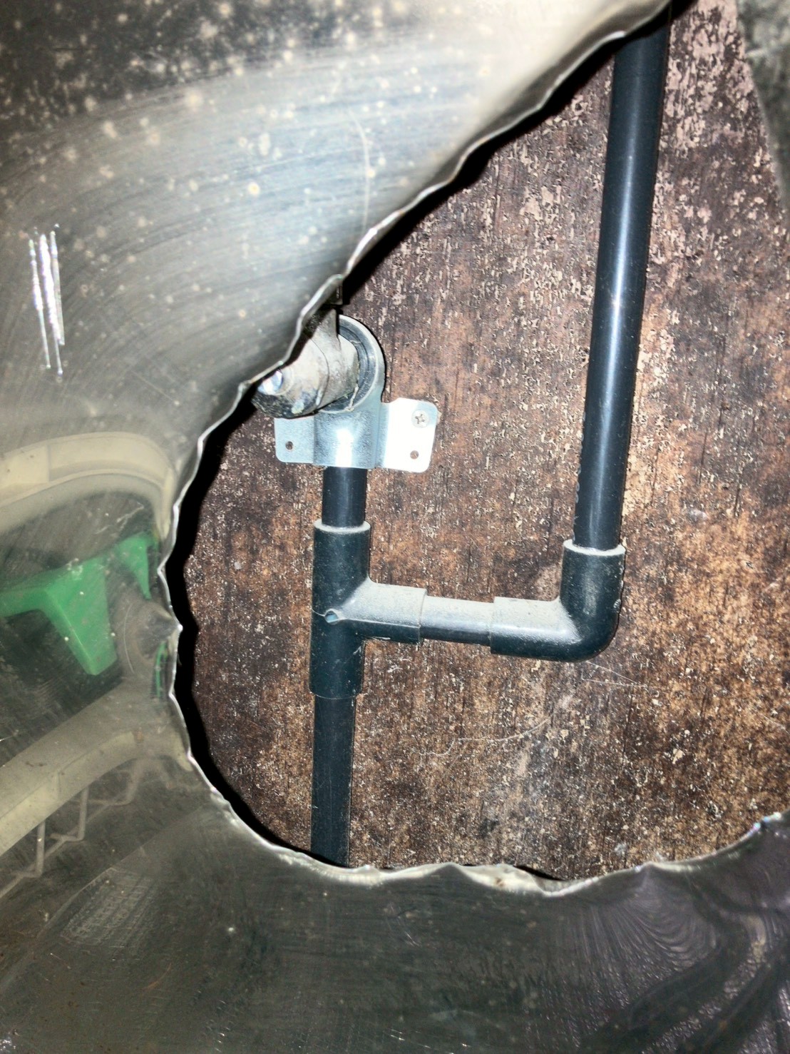 シンク下床面の配管。黒色の給水管が這い、止水金具が固定されている状態