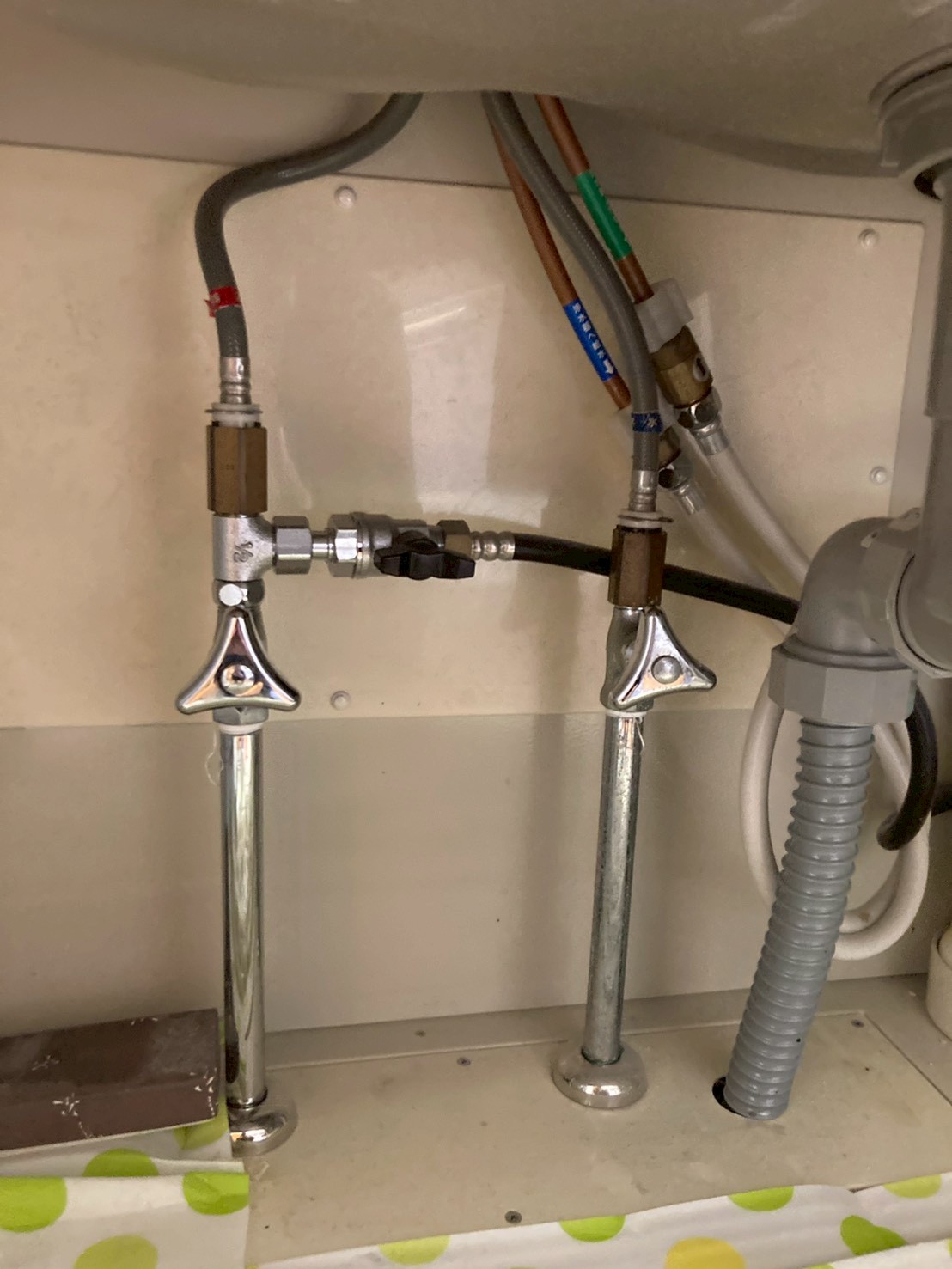 シンク下の完成後の止水栓まわり。新しい止水栓と浄水器への接続ホースが整然と配置されている