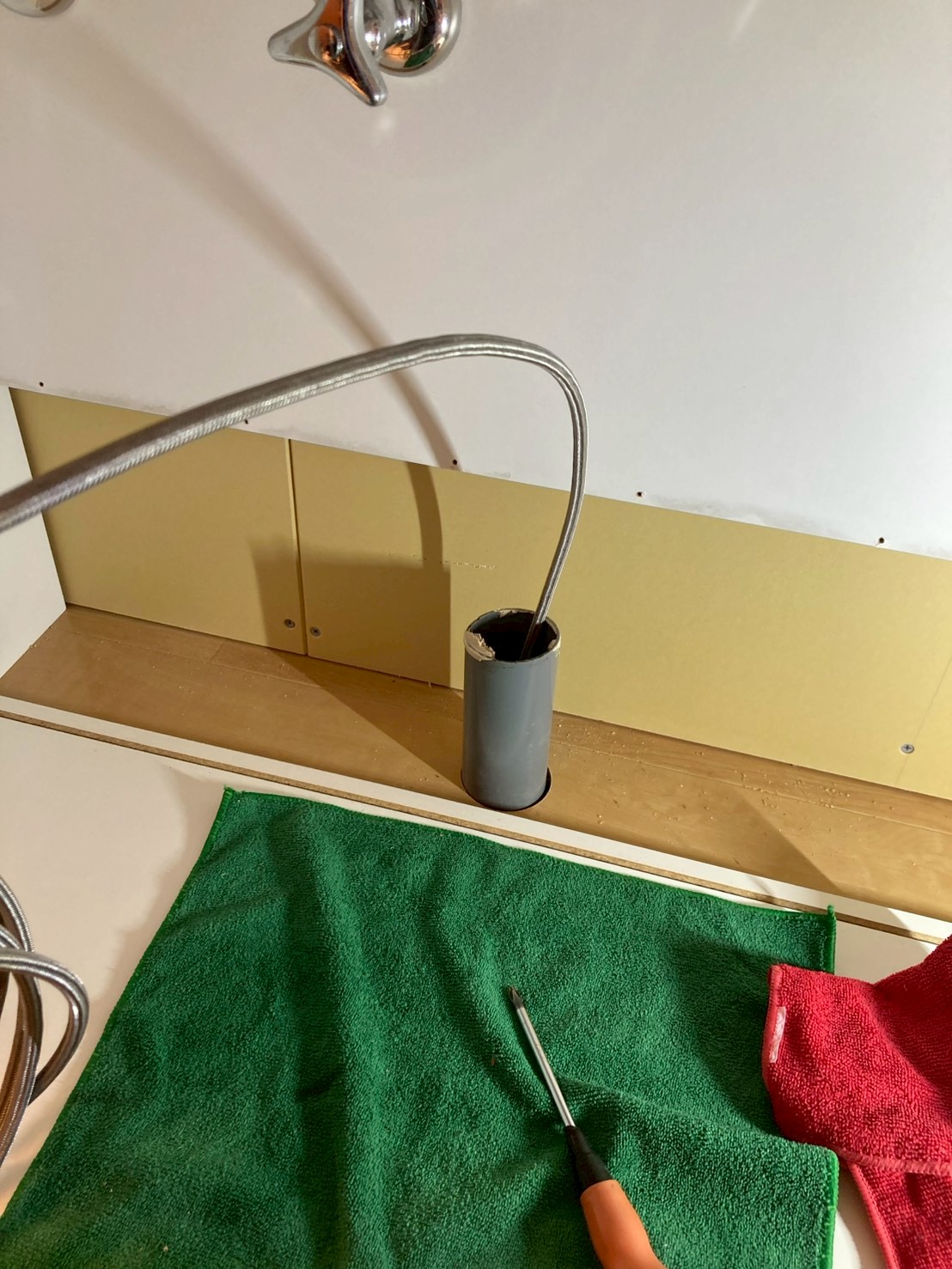 床の排水口の塩ビ管に高圧洗浄ホースを挿入して配管内を洗浄している作業中の様子