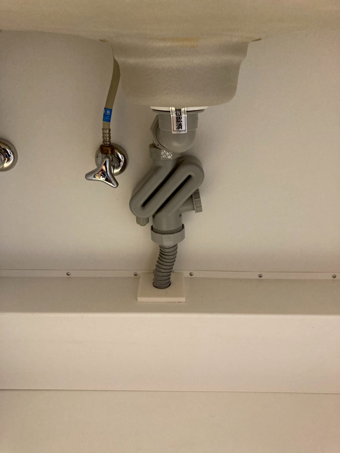 蛇腹管交換後のシンク下。新しいS字トラップと蛇腹管が整然と接続されている