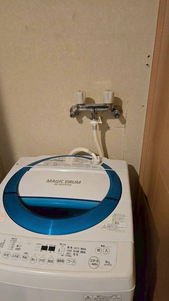 施工完了後の洗濯機置き場。壁面の二口水栓に洗濯ホースが接続されている