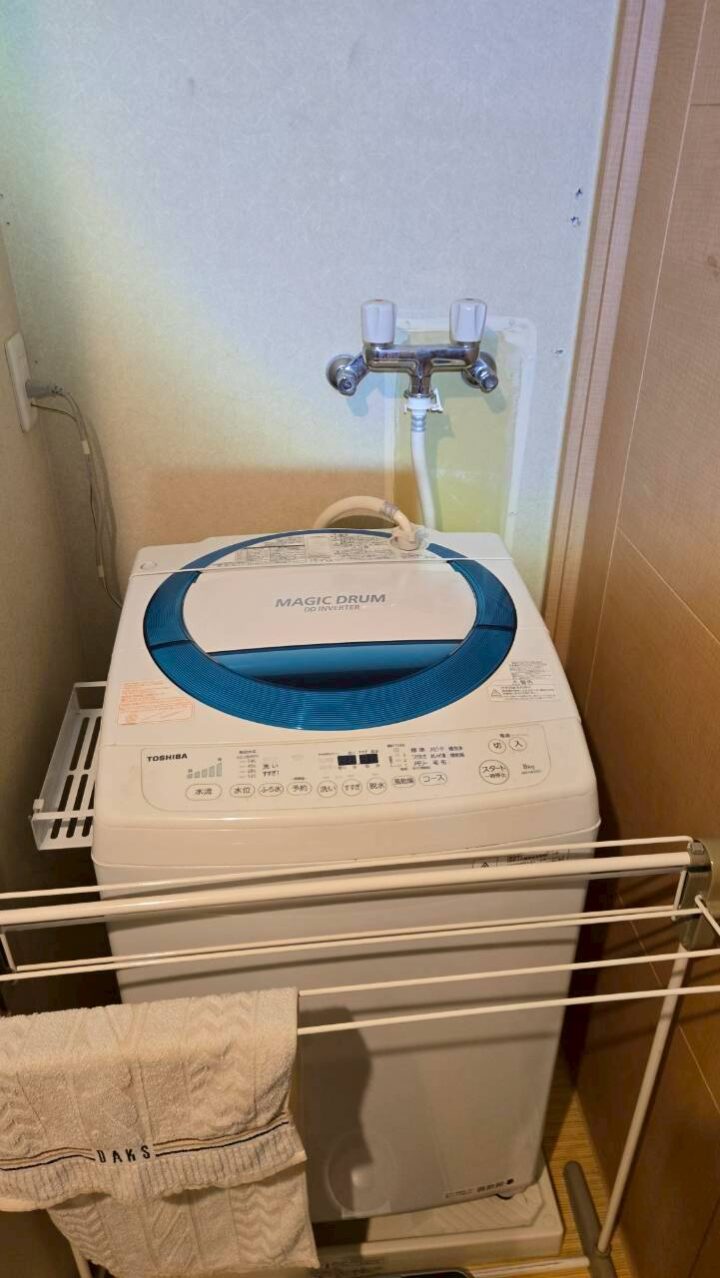 施工完了後の洗濯機置き場を引いた構図で撮影。東芝製洗濯機と壁面の二口水栓全体が確認できる