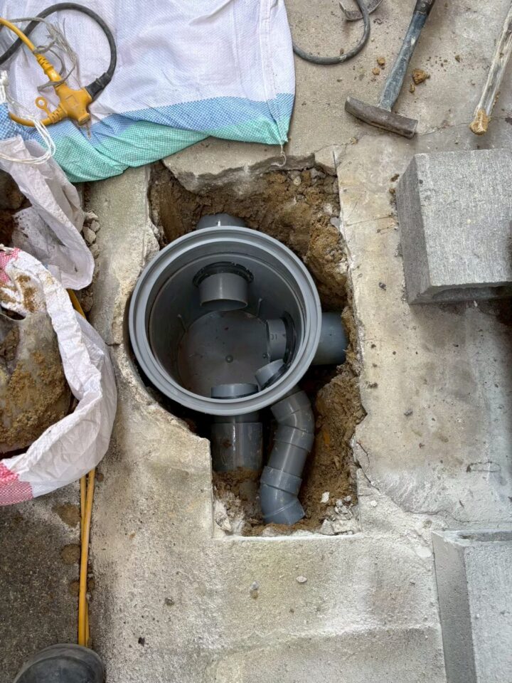 コンクリートを斫り、塩ビ管の継手を設置している施工中の様子