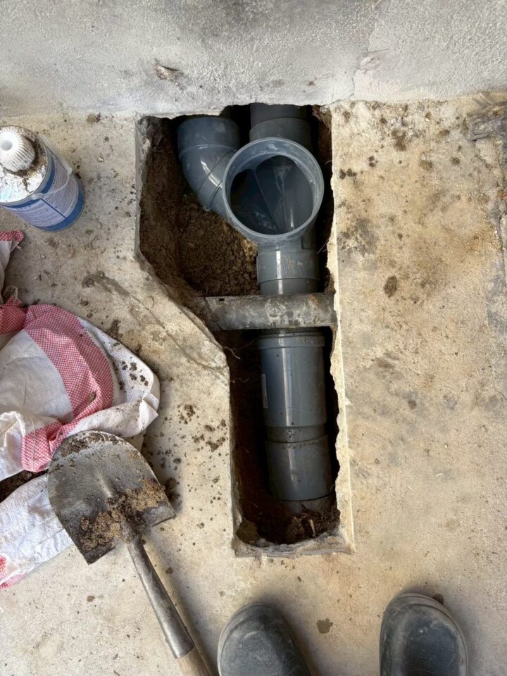 床下の溝に塩ビ管を配管している施工中の様子。接着剤を使用