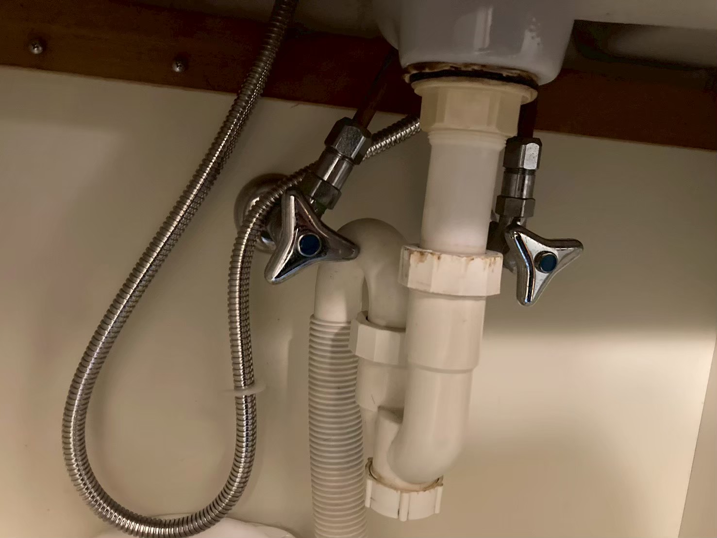 施工後の洗面台キャビネット内の別アングル。新しい三角ハンドル型止水栓2本と新しいフレキ管が接続されている