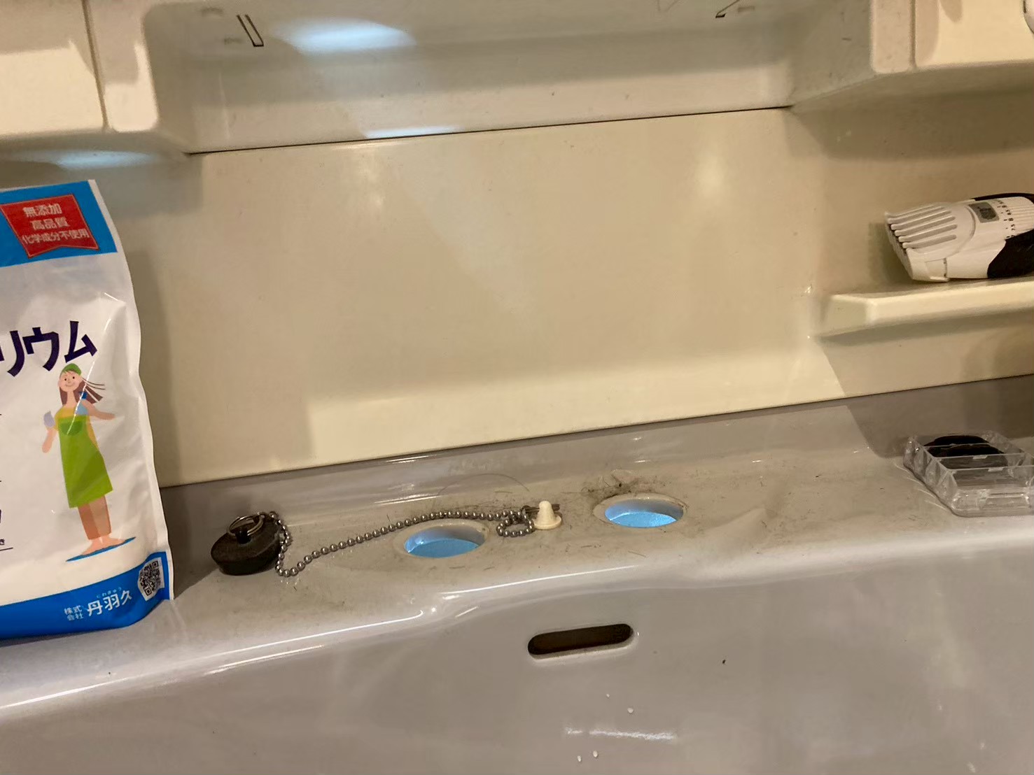 旧水栓を取り外した後の洗面台上面。3つの取付穴が露出し、ポップアップ排水のチェーンと軸が残っている