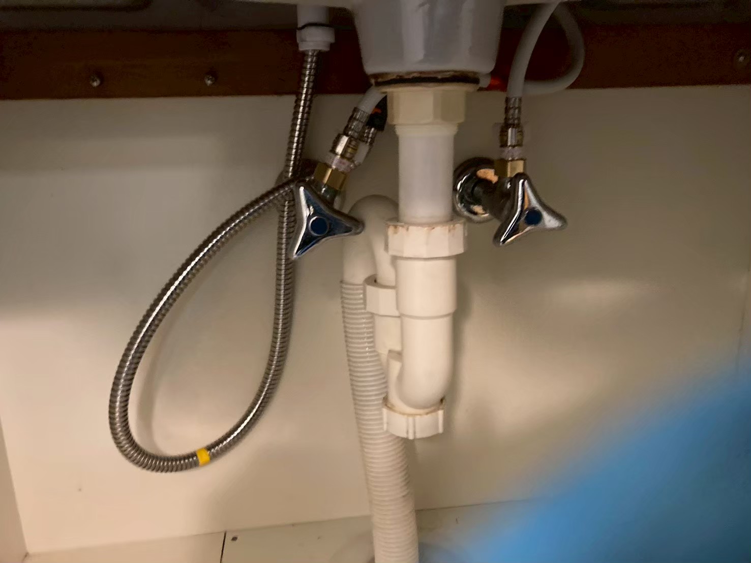 施工後の洗面台キャビネット内。新しい止水栓2本に新しいステンレス製フレキ管が整然と接続されている