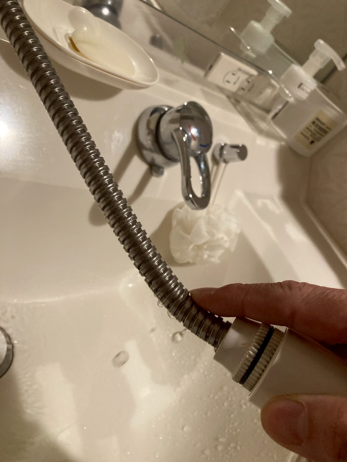 洗面台のシャワーホース接続部から水が滴り落ちている水漏れ箇所のアップ