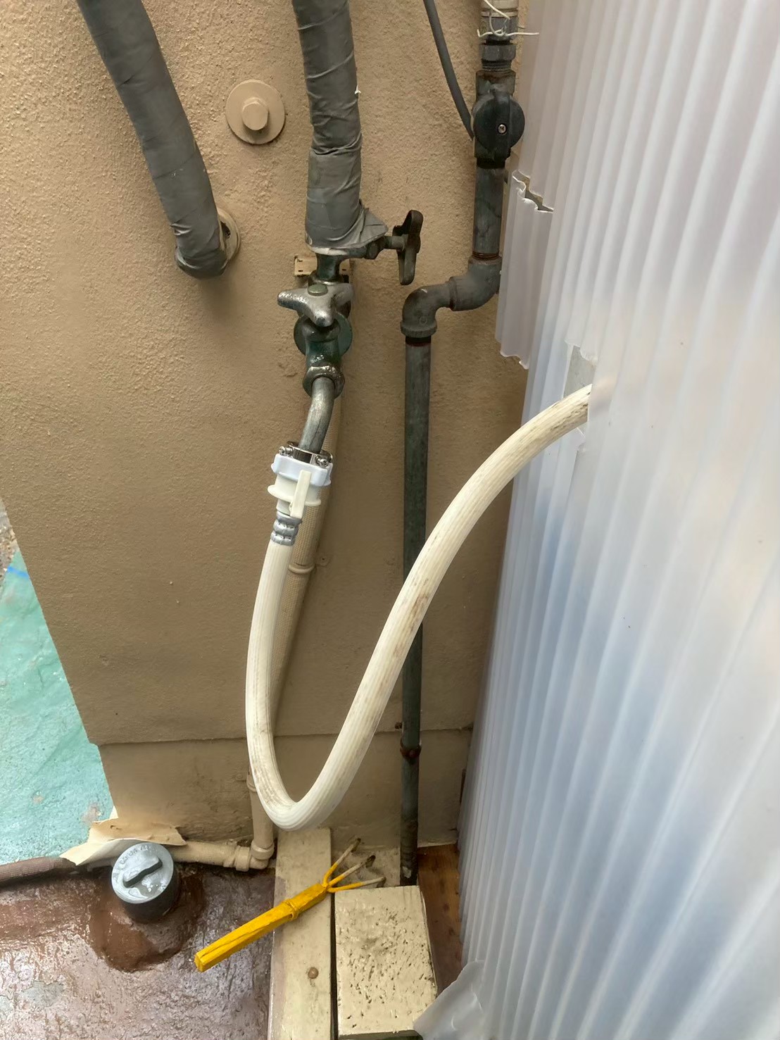 作業前の洗濯給水水栓全景。古いニップルが金属クランプで固定され経年劣化が見られる