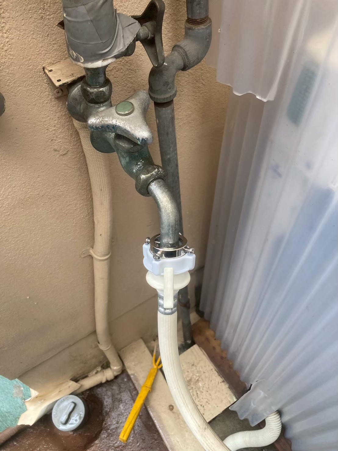 ニップル接続部のアップ。金属クランプで固定された古いニップルに水垢・緑青あり