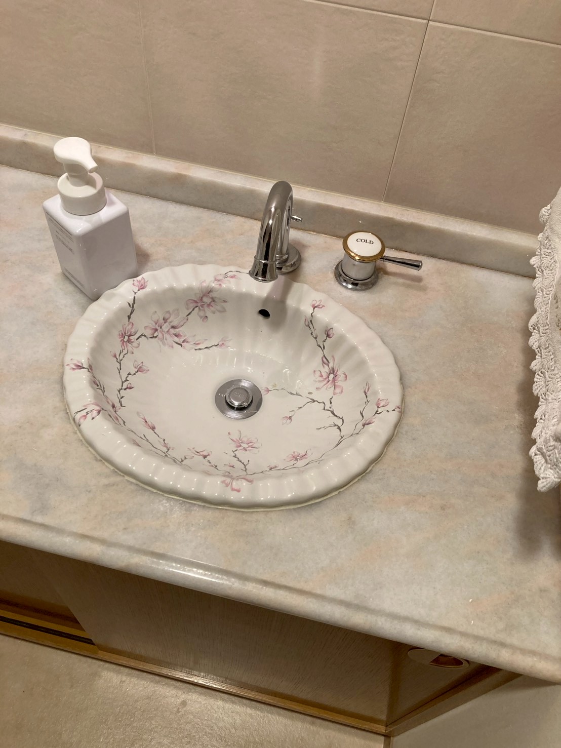 作業前のトイレ手洗い器。花柄陶器製ボウルと大理石調カウンター。見た目は清潔だが排水が詰まっている状態