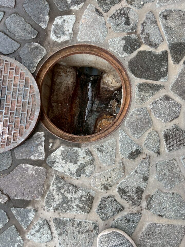 屋外の排水枡（鋳鉄製丸蓋）を開けた状態。内部が汚水で満水