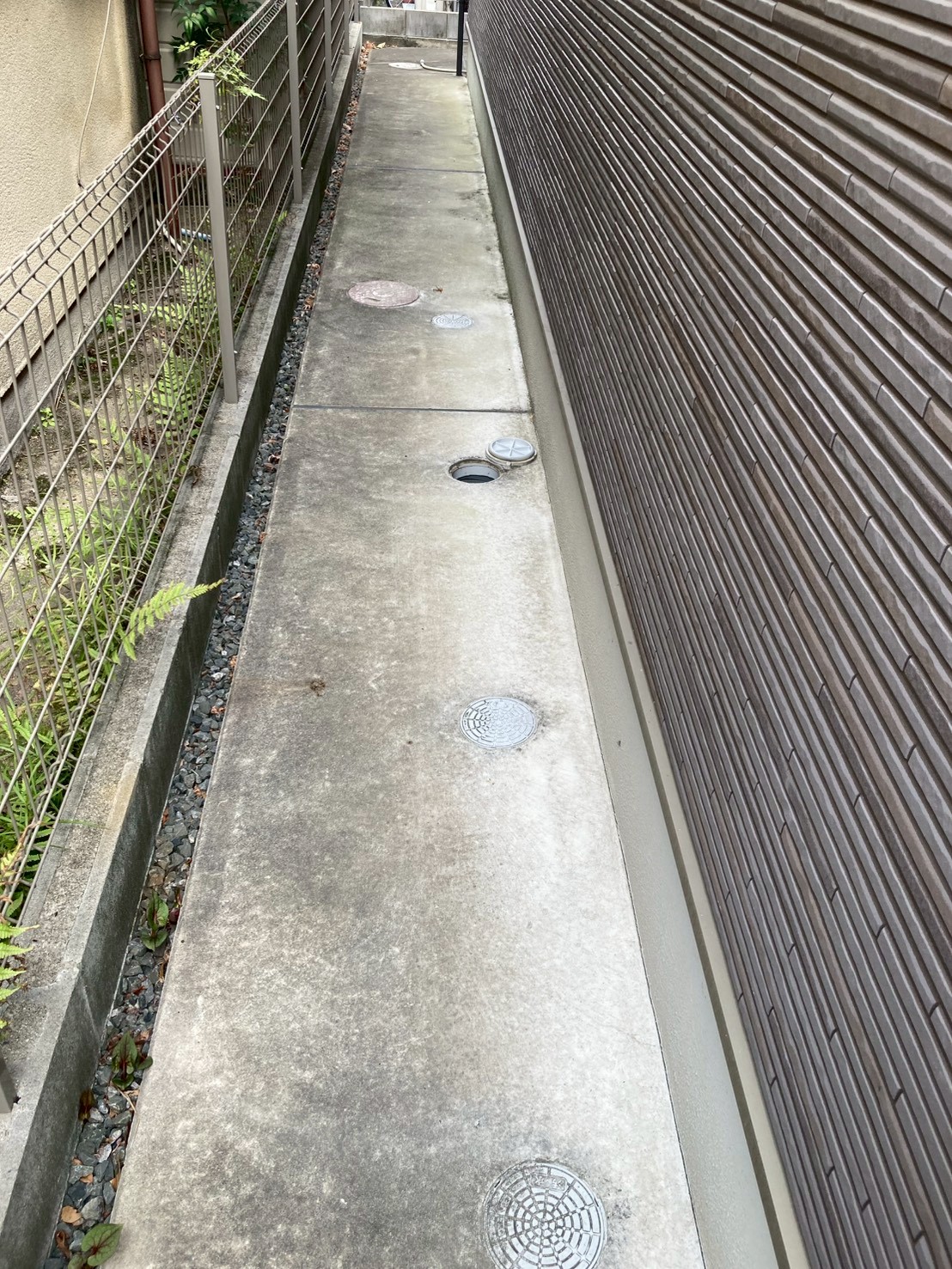 建物側面の通路に並ぶ複数の屋外排水枡の全景