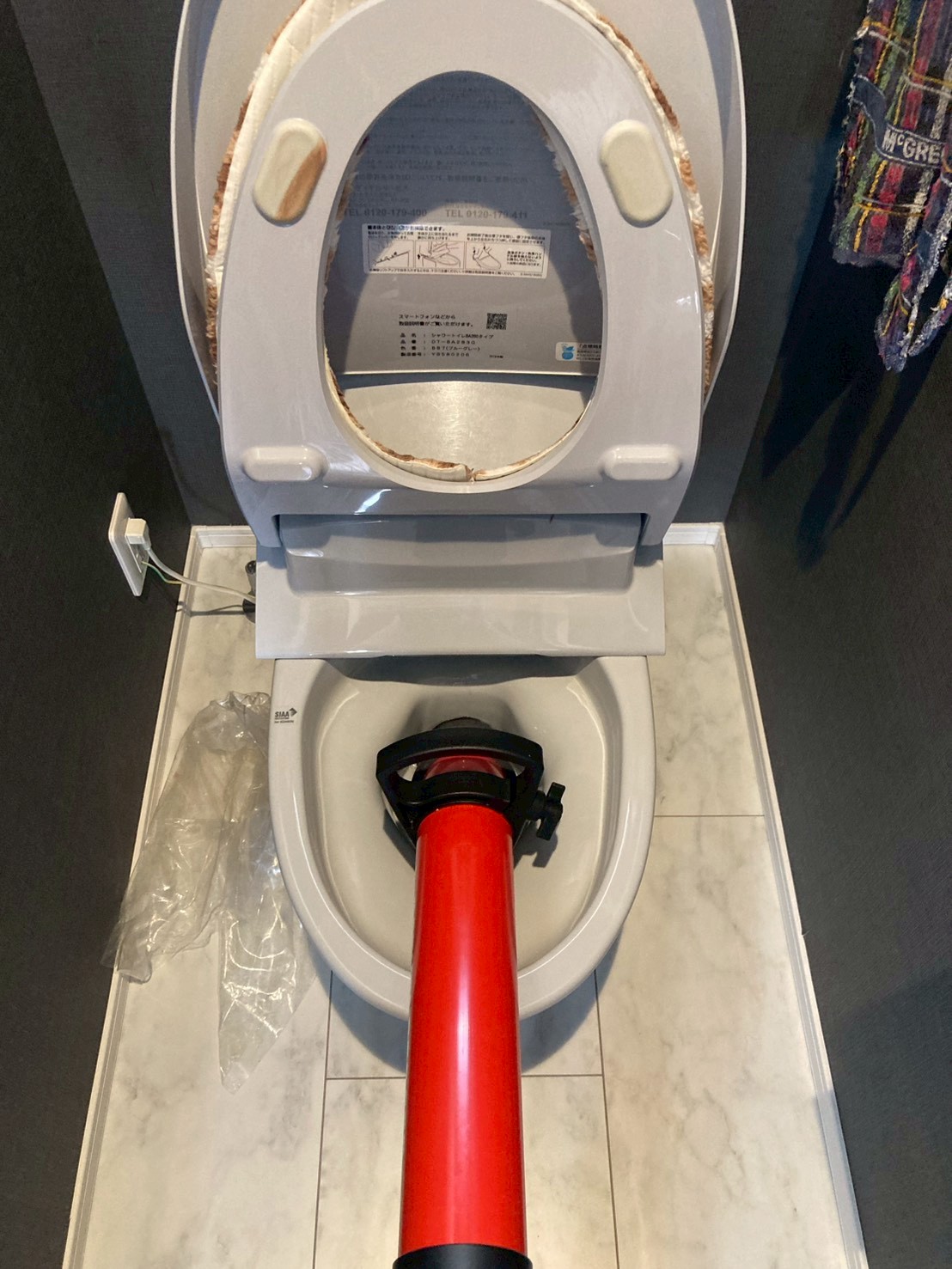 赤いローポンプを便器排水口に当てて初期対応作業中