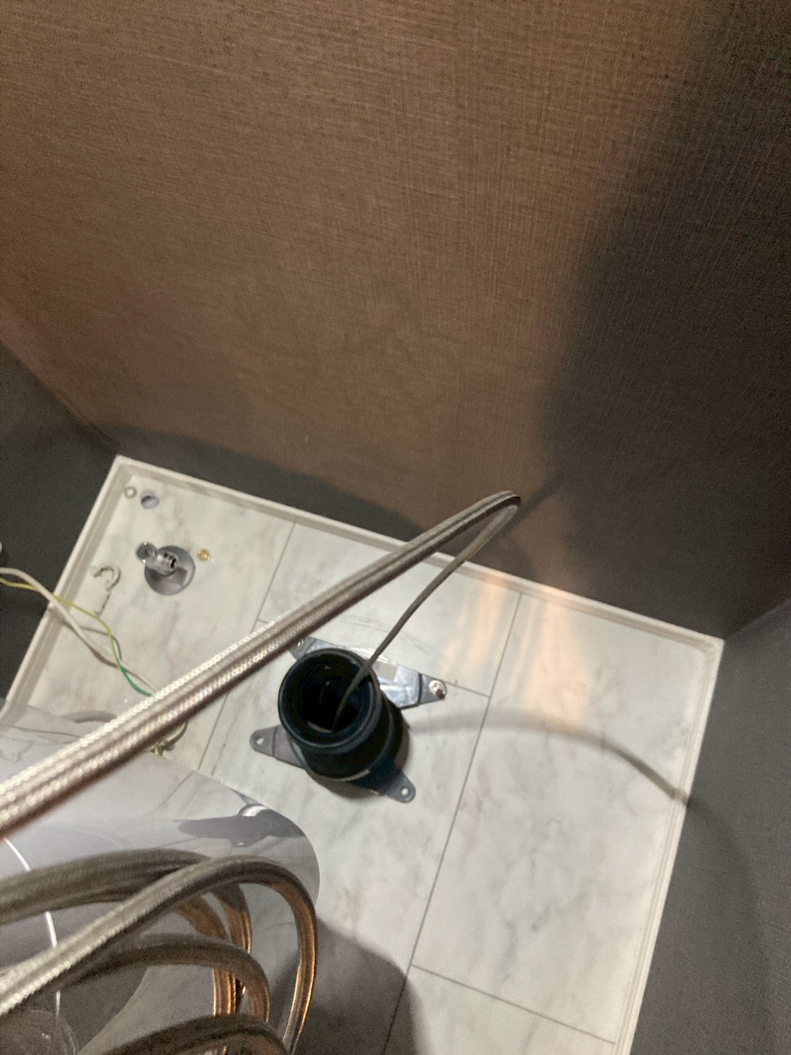 床フランジに高圧洗浄ホースを挿入して詰まり除去作業中