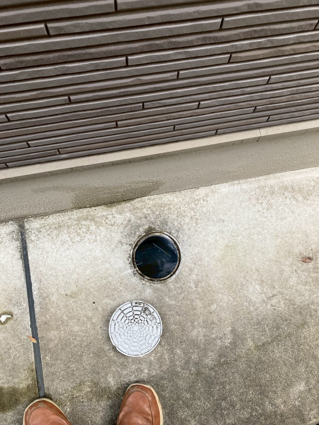 屋外排水枡の蓋を外した状態。枡内が汚水で満水になっており詰まりが屋外まで及んでいる