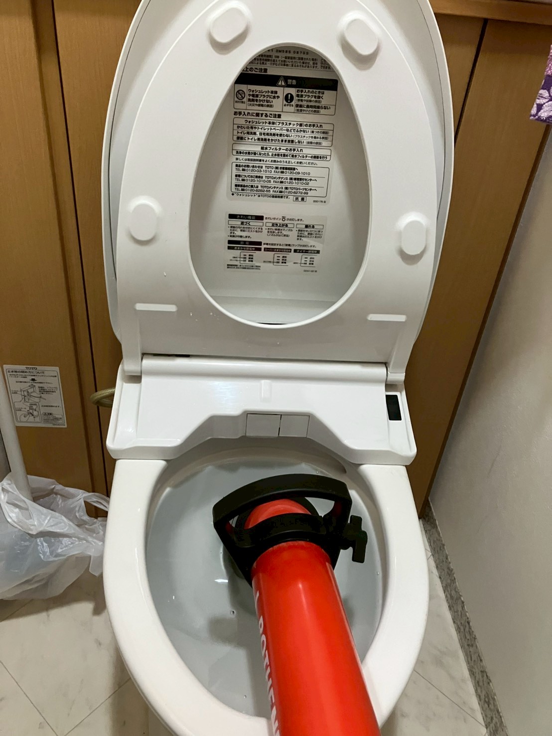 プロ用ローポンプ（真空式パイプクリーナー）を便器に挿入して詰まり除去作業中