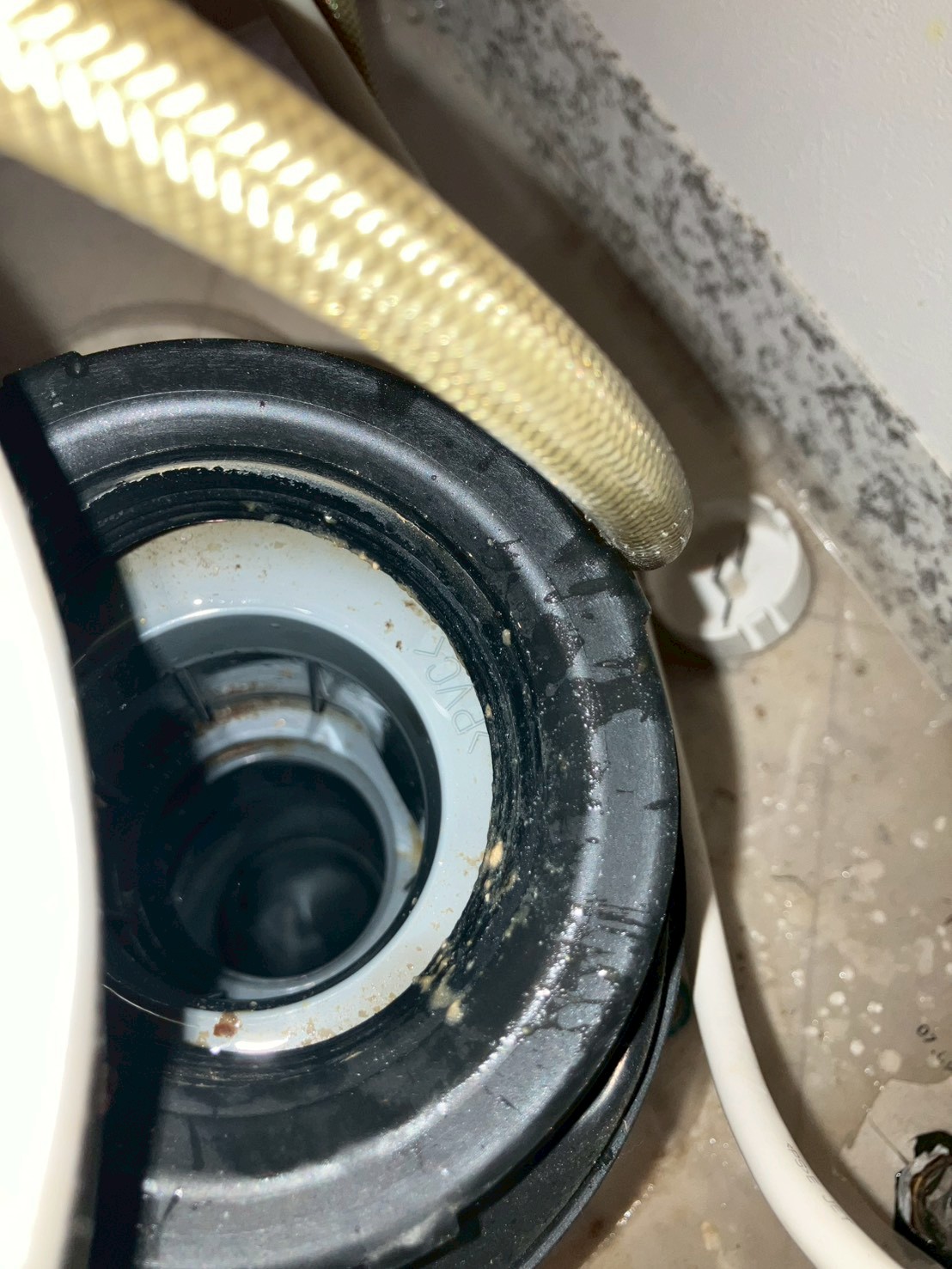 排水アダプター部分のアップ。黒いゴムパッキンにスケールや錆状の汚れが固着している