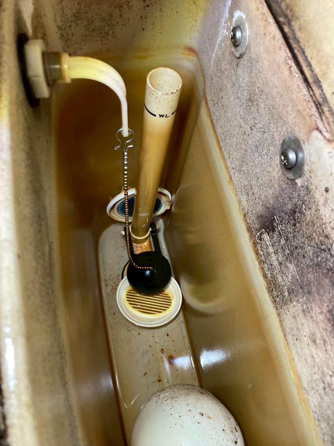 タンク内部の施工前の状態。旧型サイフォン管・フロートバルブ・フロートボールが茶色く着色・劣化している