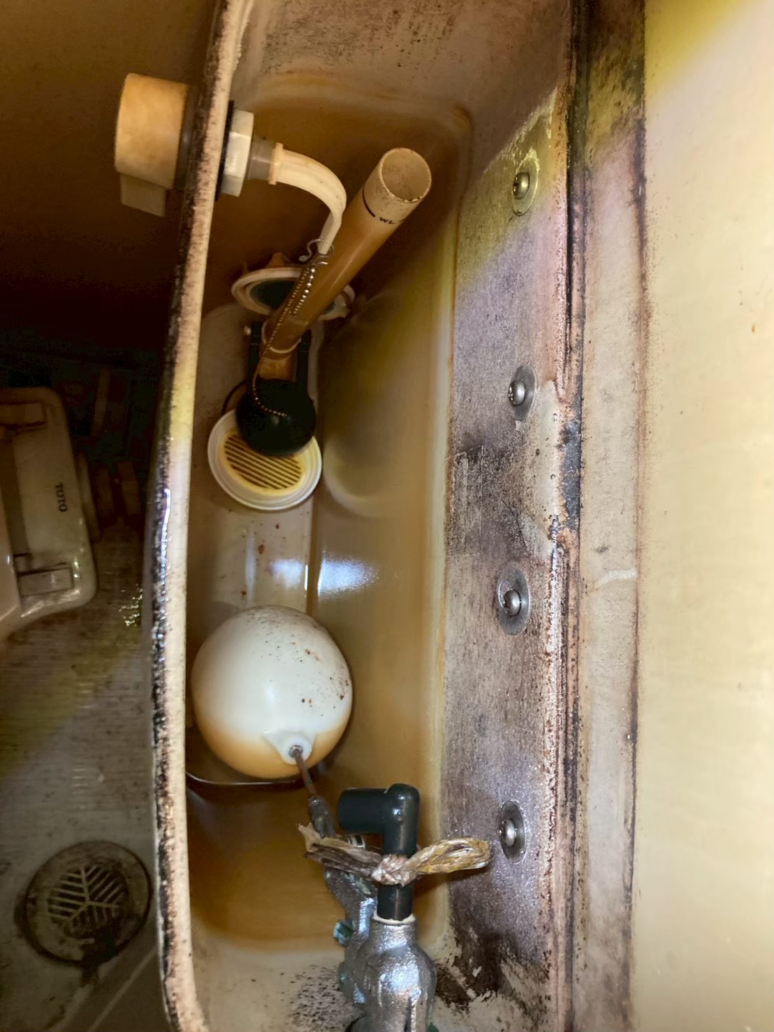 タンク内部の広角写真。ボールタップ・フロートボール・サイフォン管が旧式で全体的に汚れ・劣化が進んでいる